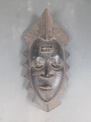 un masque en bois accroché au mur d'une pièce