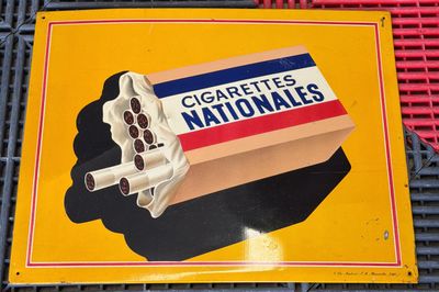 une enseigne indiquant « Cigarettes Nationales » sur la façade d'un immeuble