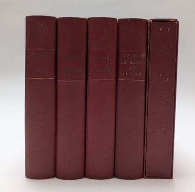cinq livres rouges sont alignés sur une surface blanche