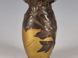 un vase en or orné d'un oiseau, posé sur une table