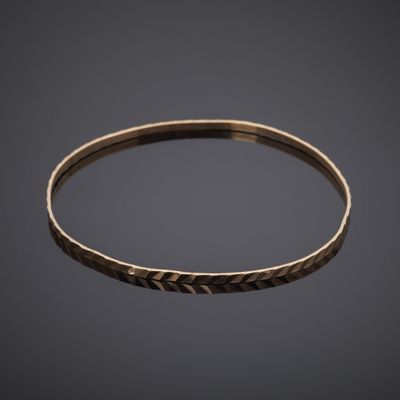 a close up of a gold bang bracelet with a textured design