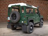 a green and white jeep parked in front of a brick wall