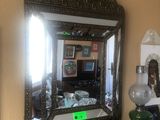 un miroir accroché au mur au-dessus d'un bureau sur lequel se trouve une lampe