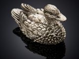un gros plan d'une figurine de canard en argent posée sur une surface noire