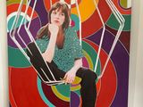 une photo d'une femme assise sur une chaise devant un tableau
