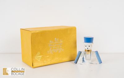 une petite bouteille en verre avec un bouchon bleu, à côté d'une boîte jaune