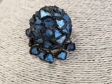 a close up of a blue flower broochle on a mannequin