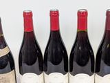 six bottles of red wine are lined up on a table