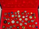 une boîte rouge remplie d'une multitude de broches de toutes sortes