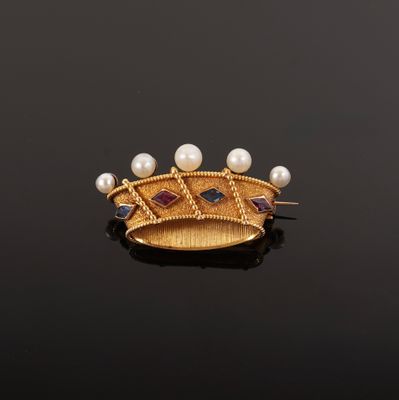 a close up of a gold broochle with pearls on a black surface