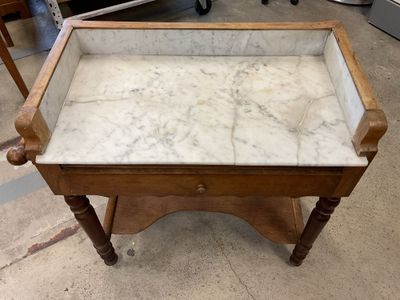 an old wooden table with a marble top in a room