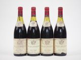 quatre bouteilles de vin sont alignées sur une surface blanche