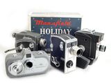 Trois appareils photo à l'ancienne sont posés à côté d'une boîte de cadeaux de Noël