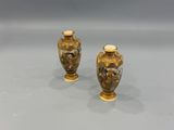 two gold vases sitting on top of a table next to each other