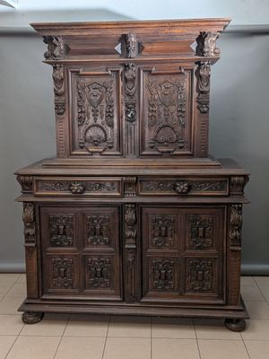 une vieille armoire en bois ornée de sculptures sur le dessus, dans une pièce