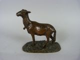 statue en bronze représentant une chèvre posée sur un rocher, sur fond blanc