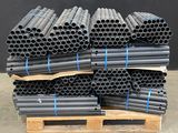 pile de tuyaux noirs empilés sur une palette devant un mur noir