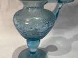un vase en verre bleu muni d'une anse, posé sur une table
