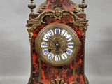 a red and gold clock with a white face