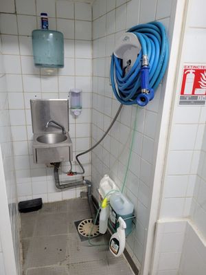 une douche avec un tuyau et un lavabo dans la salle de bains