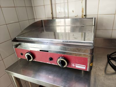 stainless steel counter top with three burners on it in a kitchen