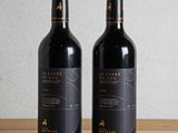 two bottles of wine sitting on a wooden table next to each other
