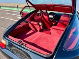 une voiture bleue avec un intérieur rouge garée sur le bord de la route