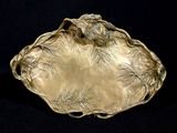 une assiette en or ornée d'un oiseau sur fond noir