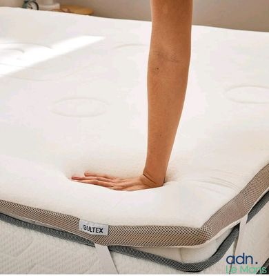 a woman standing on top of a mattress in a room