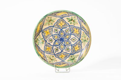 une assiette décorative posée sur un socle, sur une surface blanche