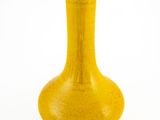 un vase jaune posé sur une surface blanche
