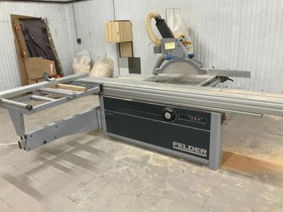 une photo d'une scie circulaire à table dans un atelier, avec une machine en arrière-plan