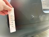 a person holding a measuring tape on the front of a car