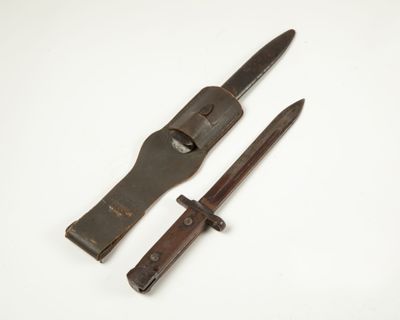 un vieux couteau et un porte-couteau posés sur une surface blanche