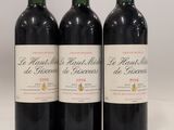 three bottles of red wine sitting on top of a white table