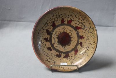 une assiette marron et rouge posée sur un support, sur une table