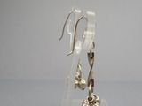 boucles d'oreilles en argent sterling posées sur un socle en acrylique transparent, sur un fond gris