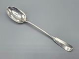 cuillère en argent à long manche posée sur une surface grise