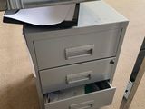 a glass top desk with a filing cabinet underneath it