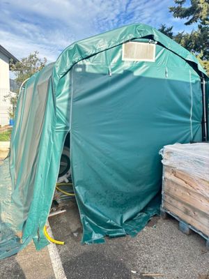une tente verte située à côté d'un tas de bois
