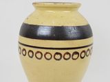 a yellow and black vase sitting on a white surface