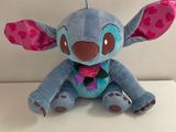 Peluche Disney Lilo assise sur une surface blanche, avec un nœud papillon rose