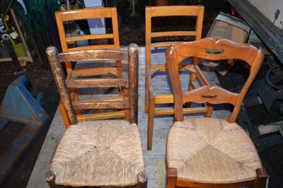 quatre chaises en bois disposées les unes à côté des autres sur un tapis