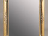 un miroir à cadre doré sur fond gris