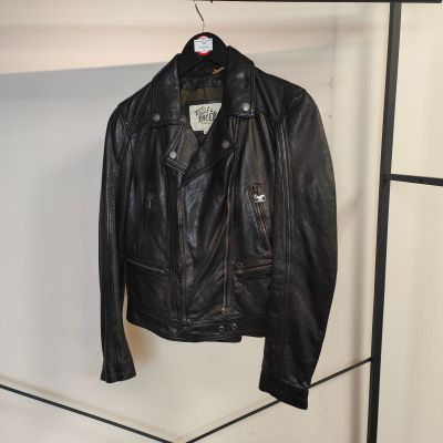 une veste en cuir noir suspendue à un portant dans un magasin de vêtements
