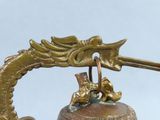 a bell with a dragon on it and a bird on top of it