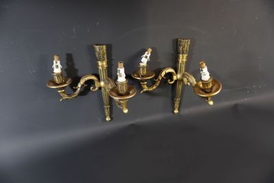 three brass wall sconces on a black wall