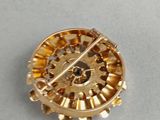 an image of a gold brooch with gears on a white surface