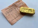 a gold bar sitting on top of a piece of paper next to a receipt