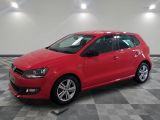 Une Volkswagen Golf rouge est garée dans une pièce dont le sol est à carreaux.